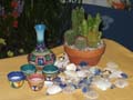 Table top decor for Mexican Baja event created by using live cactus gardens in terra cotta containers, mexican pottery and scattered seashells.